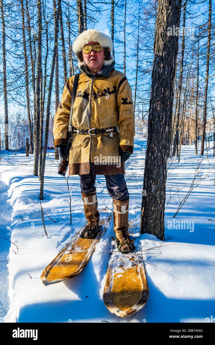 Traditional dressed Evenki hunter with snow shoes before a traditional Evenki Yurt in Tura, Krasnoyarsk Krai, Evenki state, Russia Stock Photo