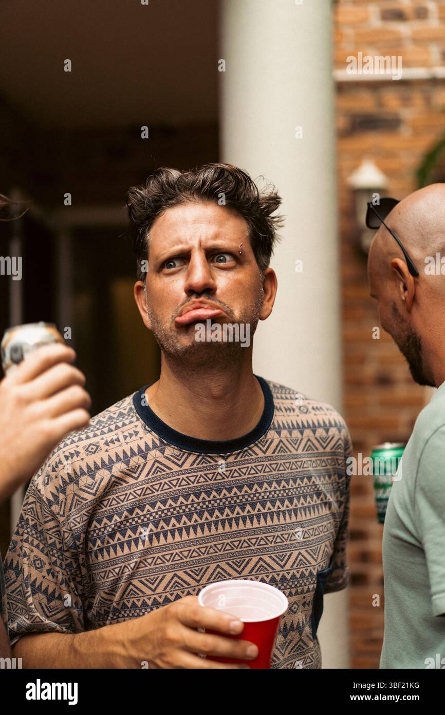 Man making a funny pout face at an outdoor party Stock Photo