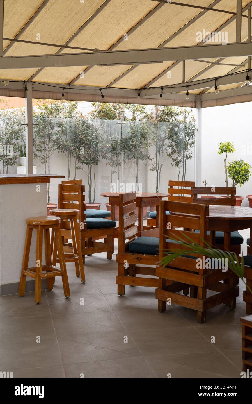 Charming outdoor dining area featuring sturdy wooden chairs, ideal for relaxing meals in a natural and inviting atmosphere with timeless style. Stock Photo