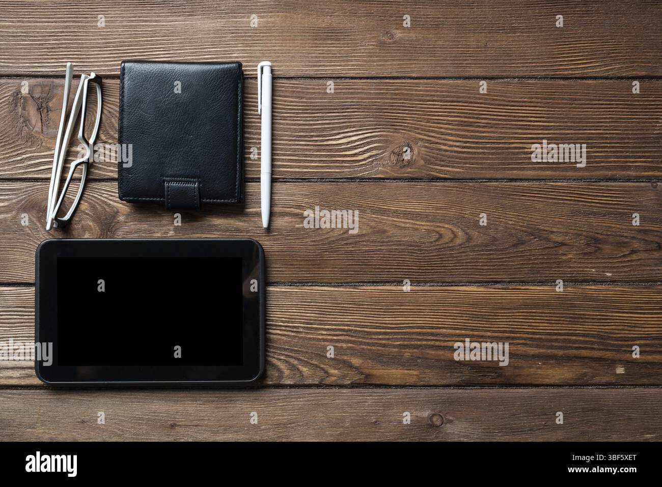 Still life of office workspace with supplies. Flat lay old hardwood desk with black leather wallet and tablet computer. Online shopping and payment. C Stock Photo