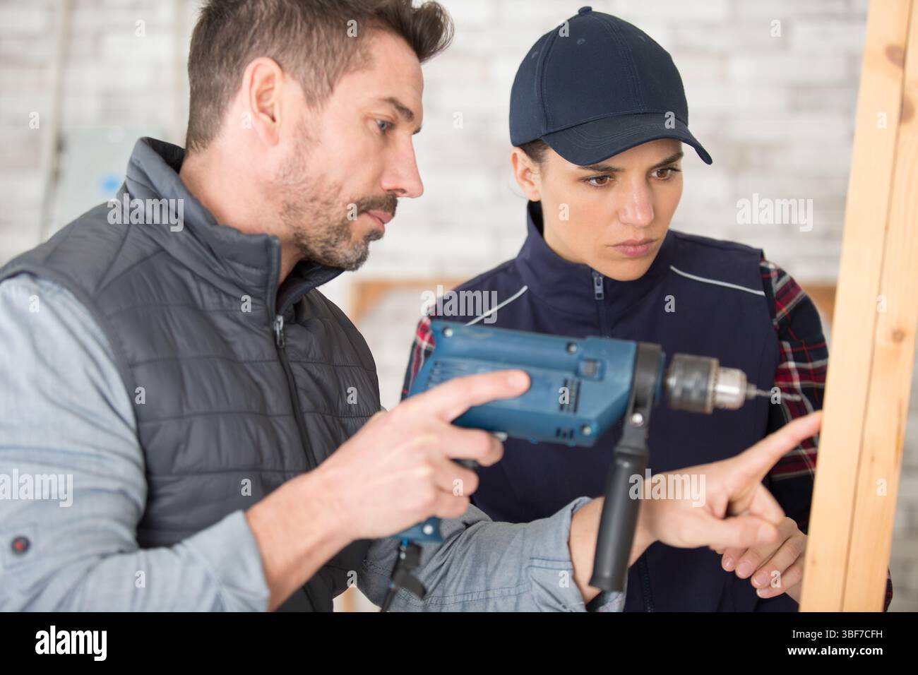 carpenter woman and man with drill in workshop Stock Photo