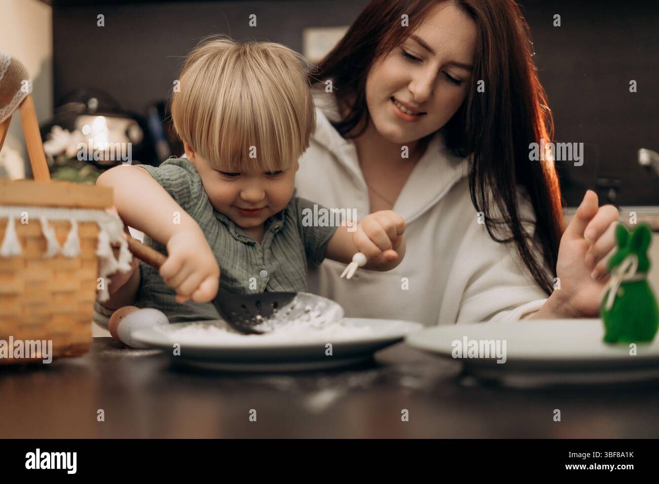 Emotional bonding moment as mother and toddler enjoy flour play in kitchen exploring spring rituals mindful connection and homeschool-inspired Stock Photo