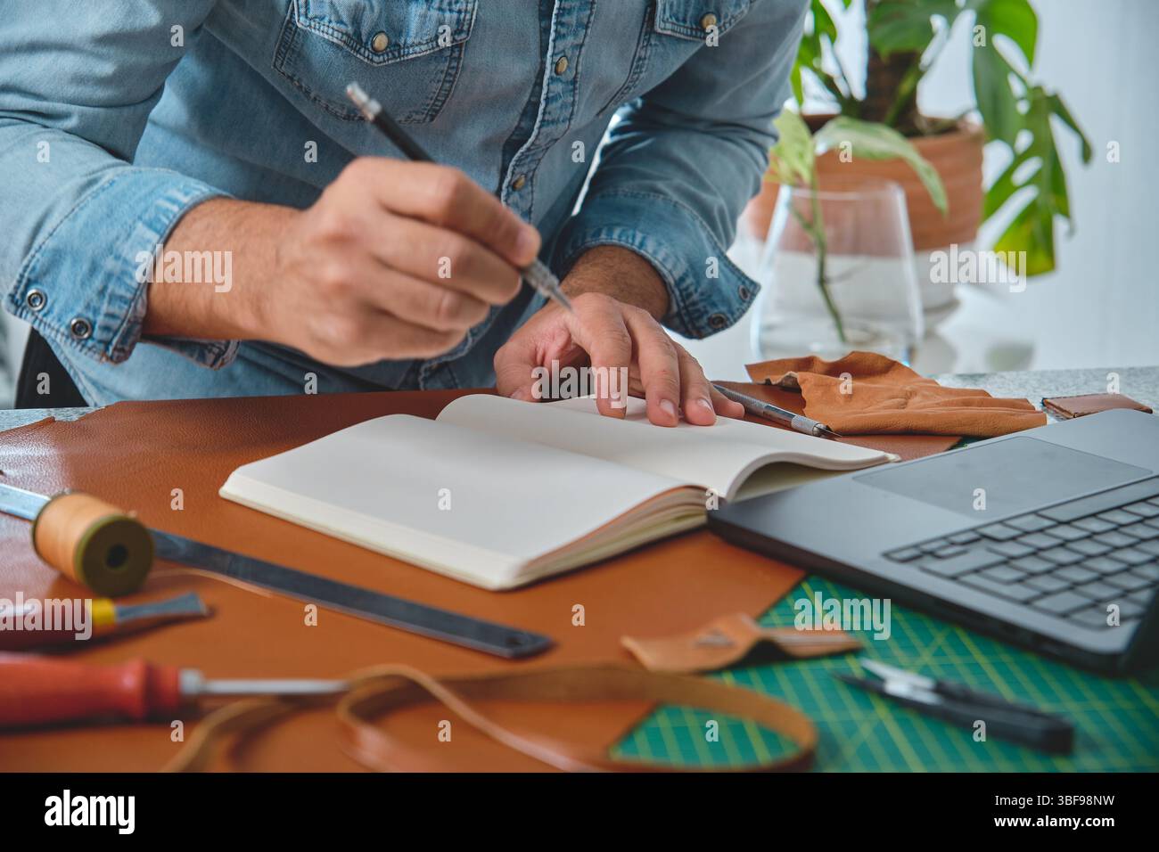 Craftsman Notebook Leather craftsman taking notes on notebook and designing new leather ...