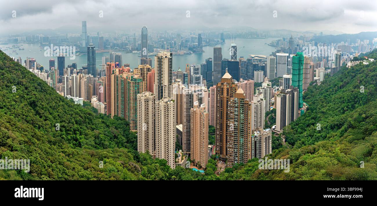 View of Hong Kong and its skyscrapers from Victoria Peak, Central and Western District, Hong Kong, China.  From Victoria Peak, visitors can enjoy a panoramic view of Hong Kong's skyline, including its iconic skyscrapers such as the International Commerce Centre and the Bank of China Tower. The view also spans Victoria Harbour, offering a striking contrast between the urban landscape and surrounding natural scenery. Stock Photo