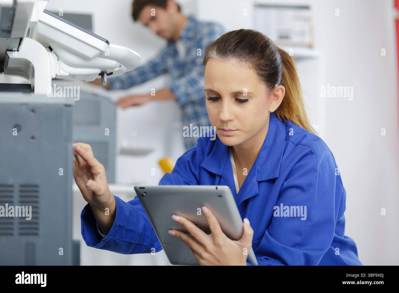 female technician fixing printer with tablet Stock Photo