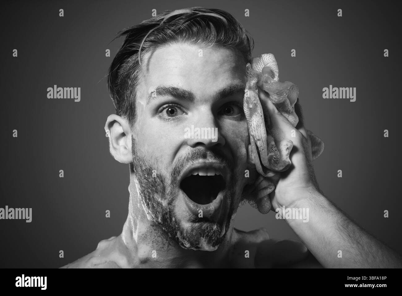 Handsome guy washing body with moisturizing shower gel. Morning routine, self hygiene, skincare and spa. Muscular man taking shower. Smiling man washi Stock Photo