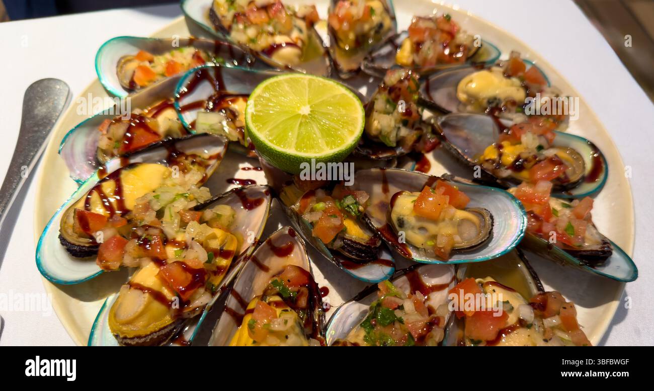 A platter of smoked New Zealand Green Lipped Mussels (Perna Canaliculus) in their shells Stock Photo
