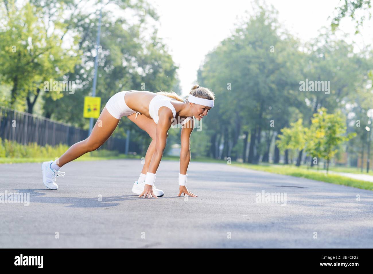 Young woman runner outdoor standing in start pose Stock Photo