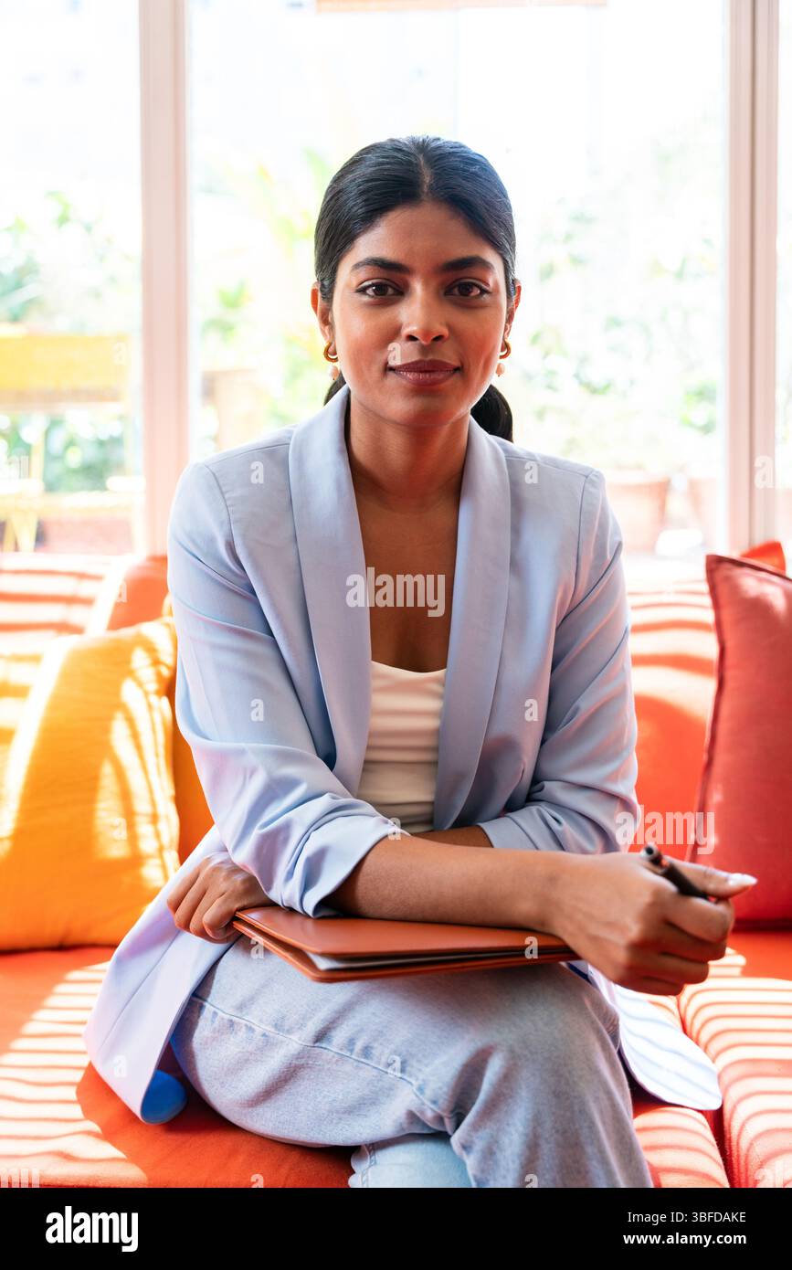 Beautiful indian business woman working in a coworking corporate company office - Young female wearing business casual clothing works in a creative st Stock Photo