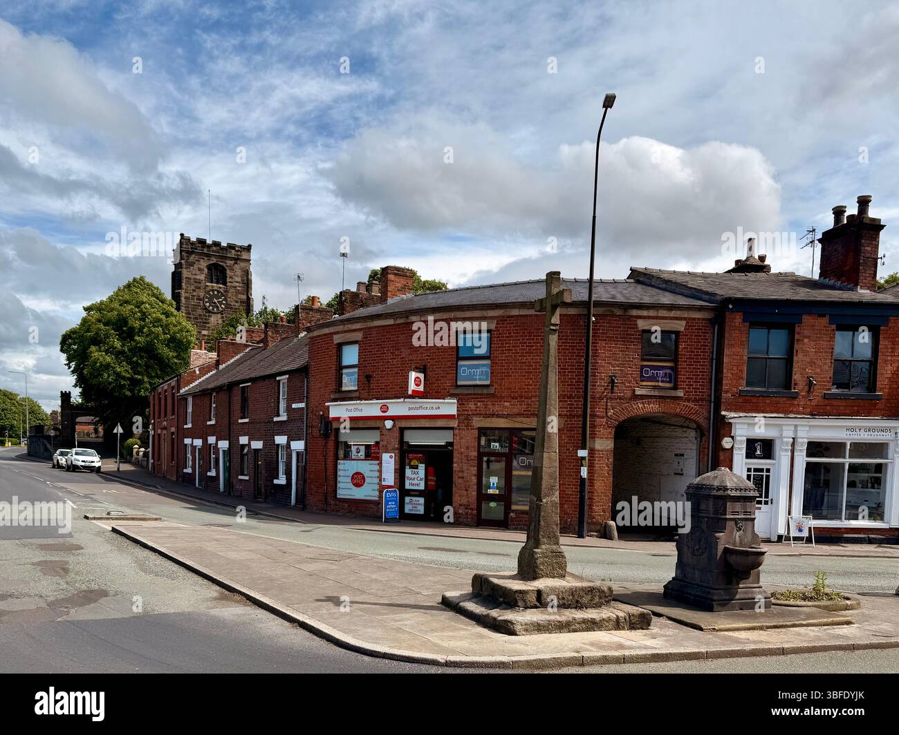 Medieval cross and drinking well on Towngate (Worden Lane)in Leyland, Lancashire. With St Andrews parish church in background - Smartphone Captured Stock Image