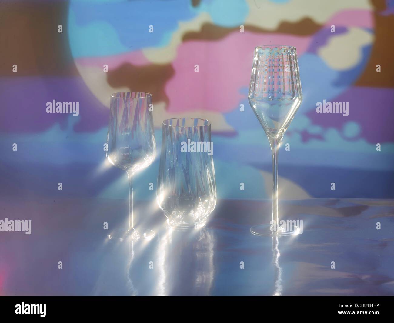 Various glasses on silver foil, behind them various colour elements, studio shot Stock Photo