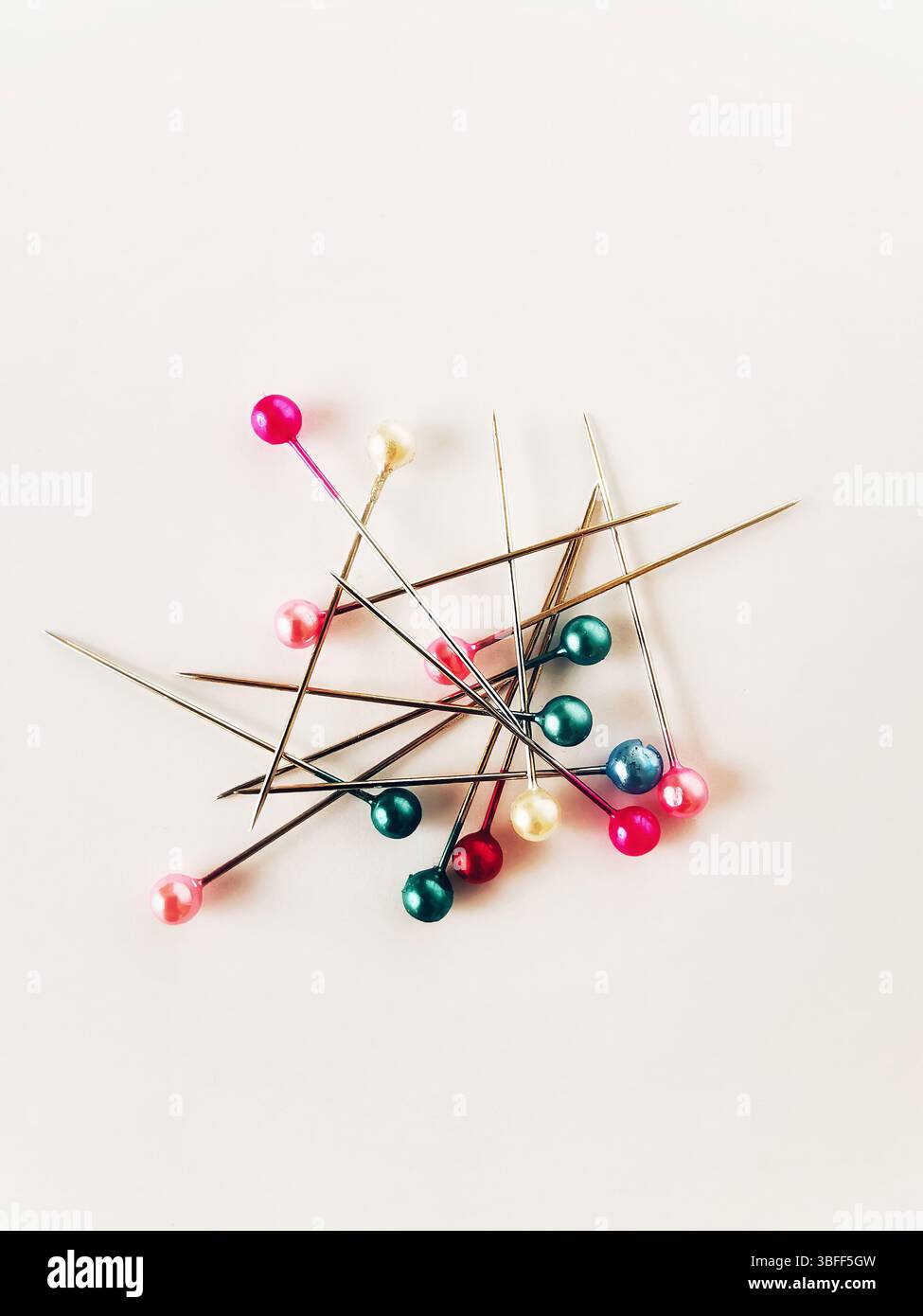 Various sewing pins with colorful heads are scattered across a light background, illustrating the vibrant tools of the crafting trade. - Smartphone Captured Stock Image
