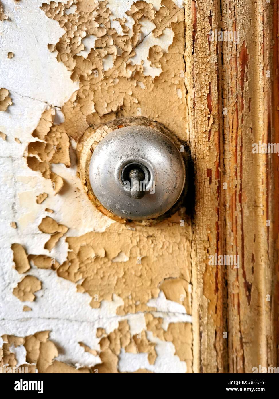 Old electrical switch mounted on weathered wood with peeling paint in a rustic setting - Smartphone Captured Stock Image
