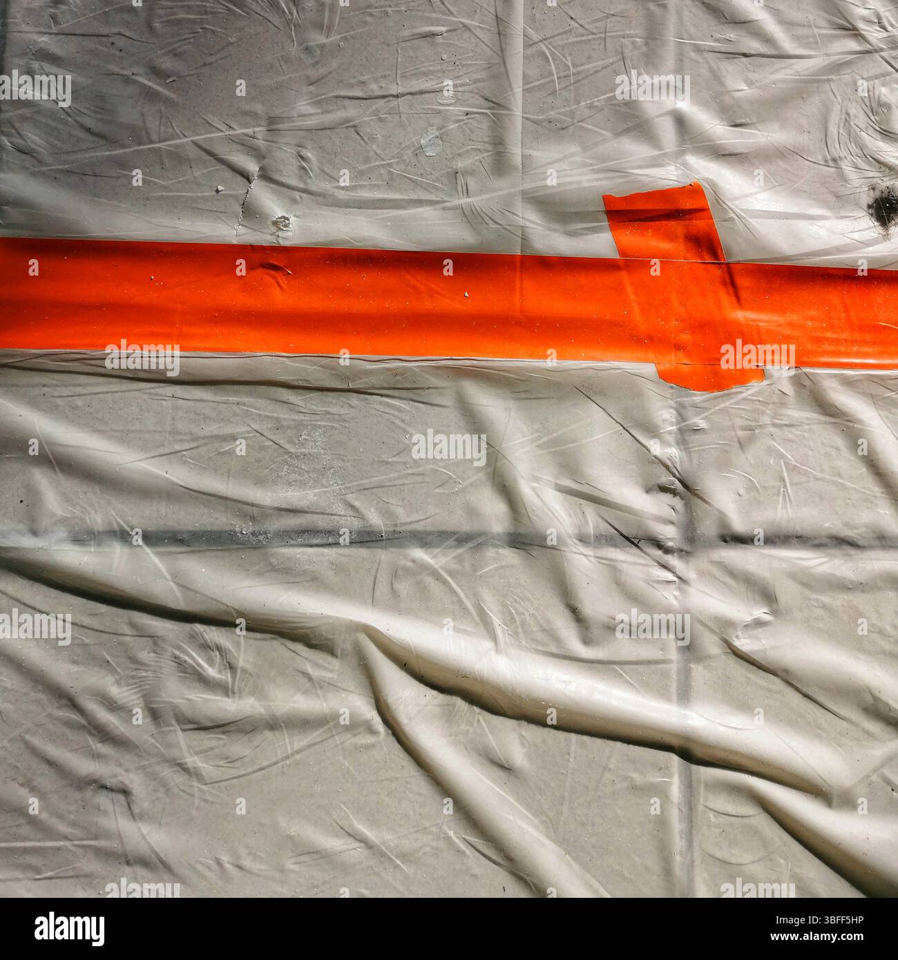 Bright orange tape stretches across a wrinkled white surface, creating a clear boundary. - Smartphone Captured Stock Image