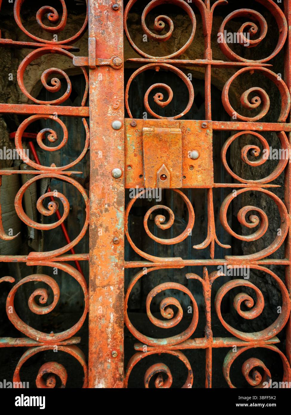 A weathered iron gate showcases detailed swirling patterns, highlighting years of exposure to the elements. - Smartphone Captured Stock Image