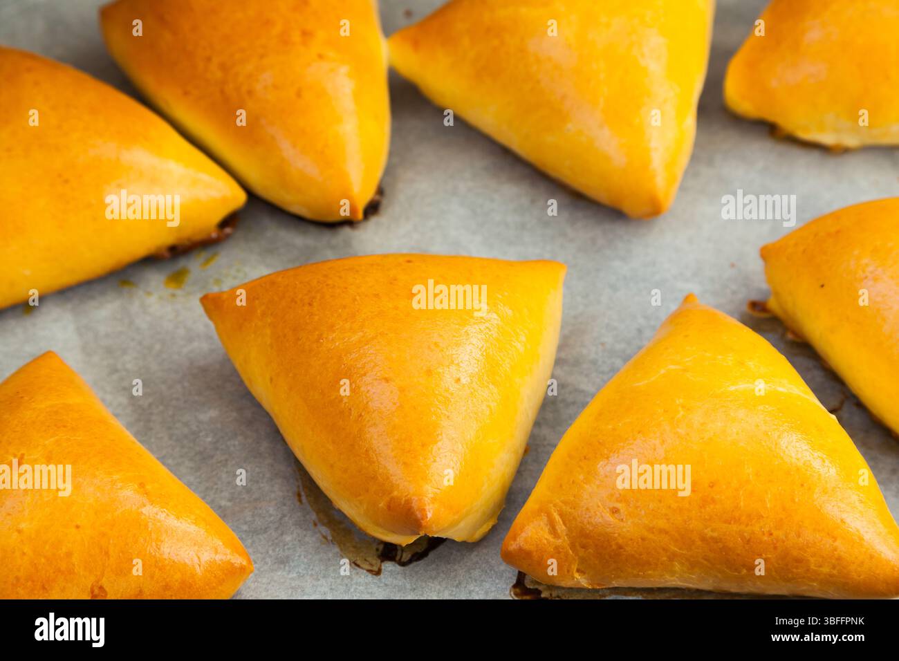 Homemade baked triangular buns lie on white parchment Stock Photo - Alamy