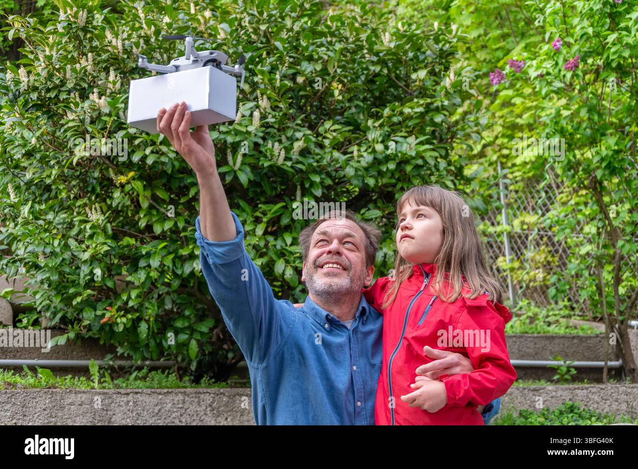 Generations are embracing technology together - a girl and her father enjoy the launch of a delivery drone Stock Photo