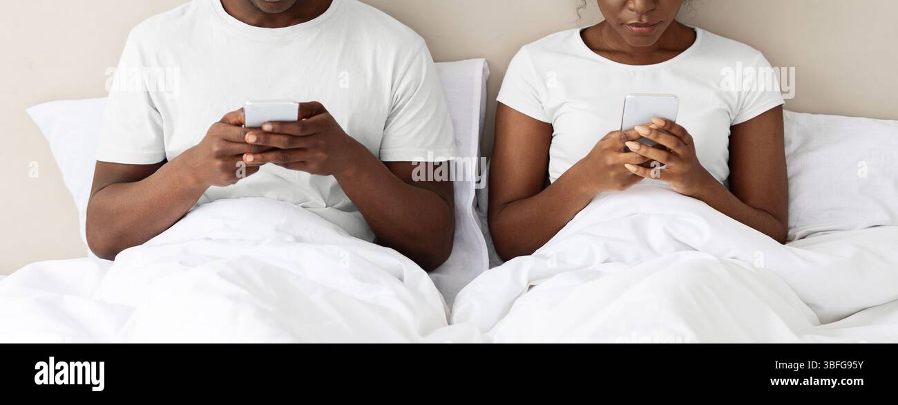 Unrecognizable black couple using smartphones in bed Stock Photo