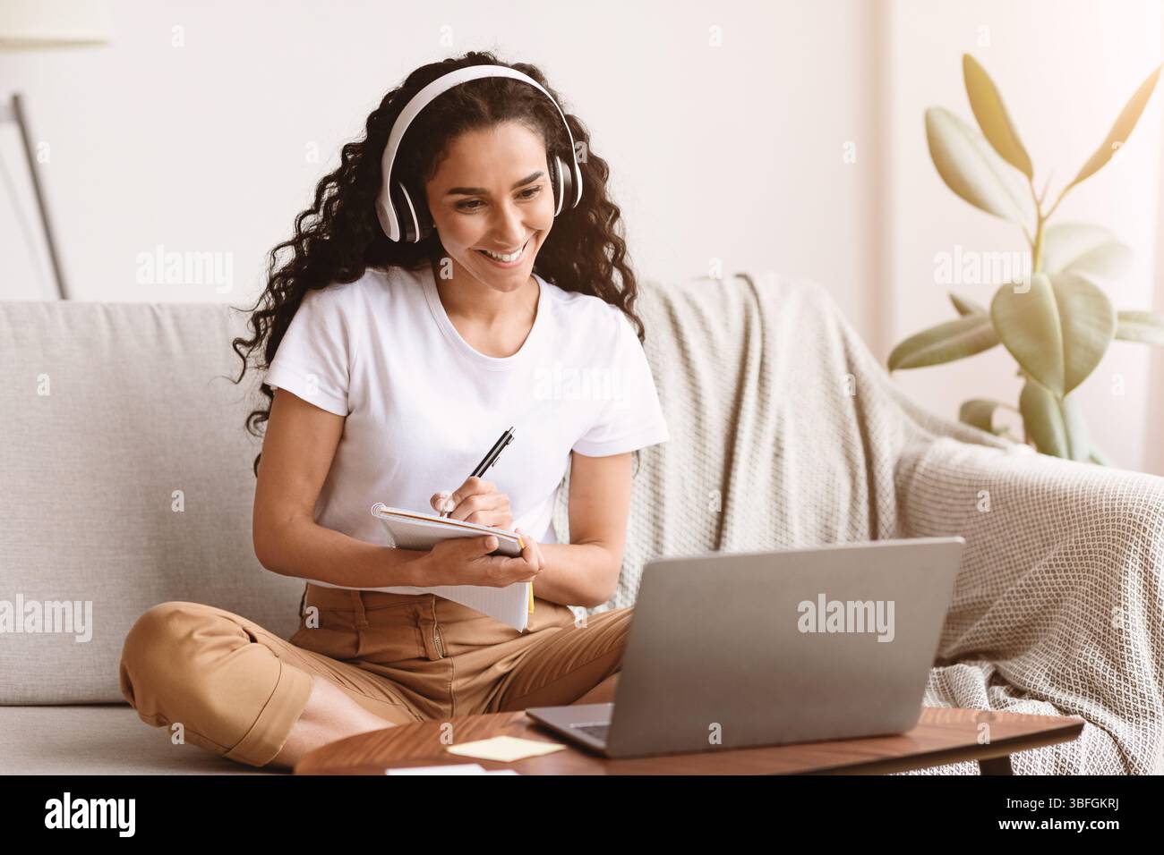 Cheerful lady attending webinar, using laptop and wireless headset Stock Photo