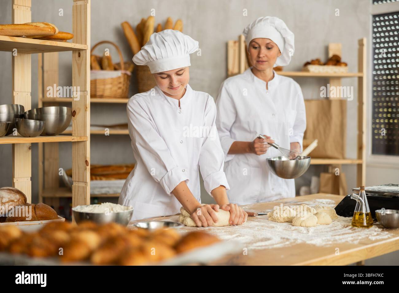 Female bakers in uniform preparing gray dough Stock Photo