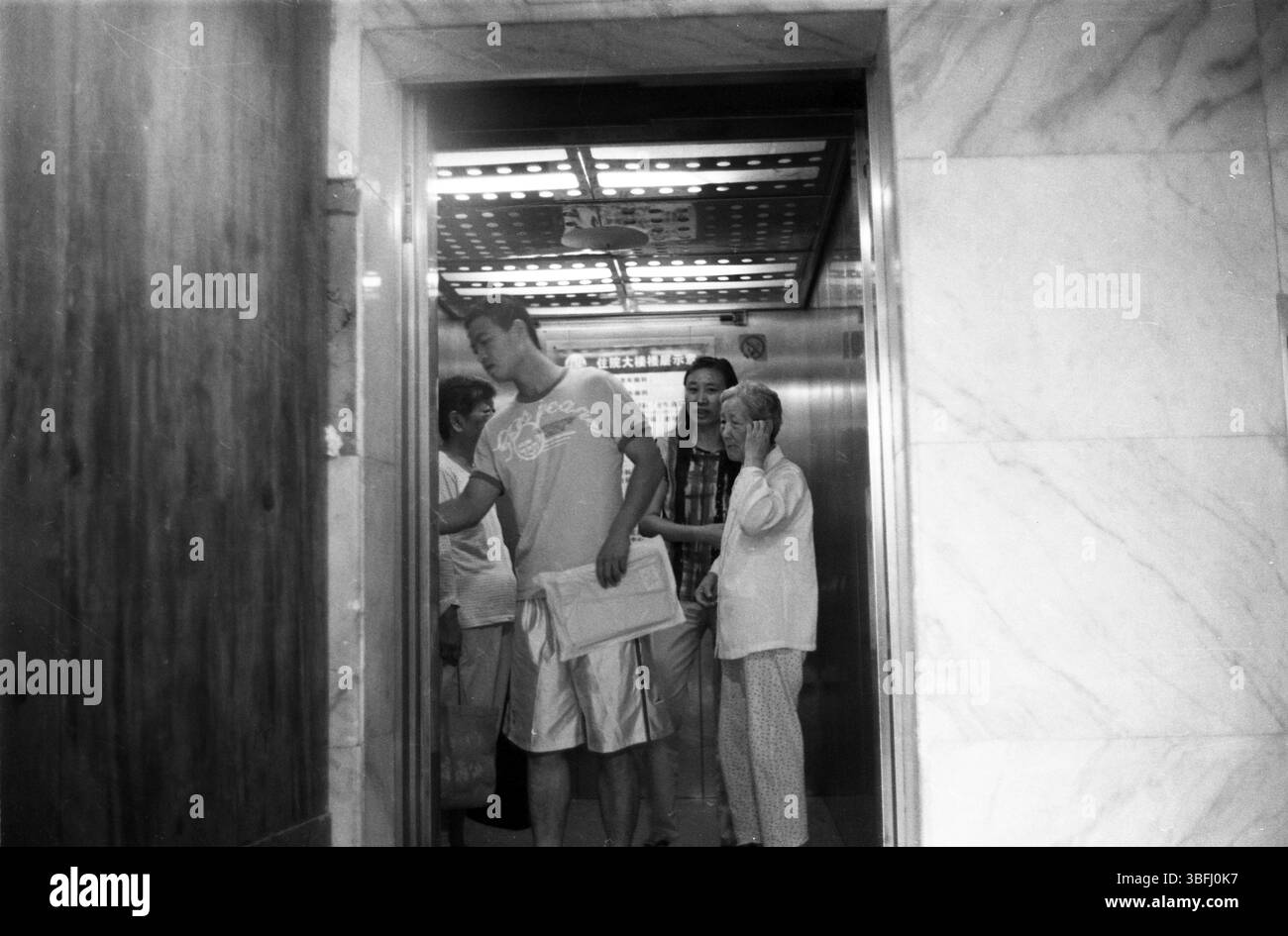 Early-2010s Hangzhou Red Cross Hospital Elevator Scene with Elderly Patient and Family Caregivers Stock Photo