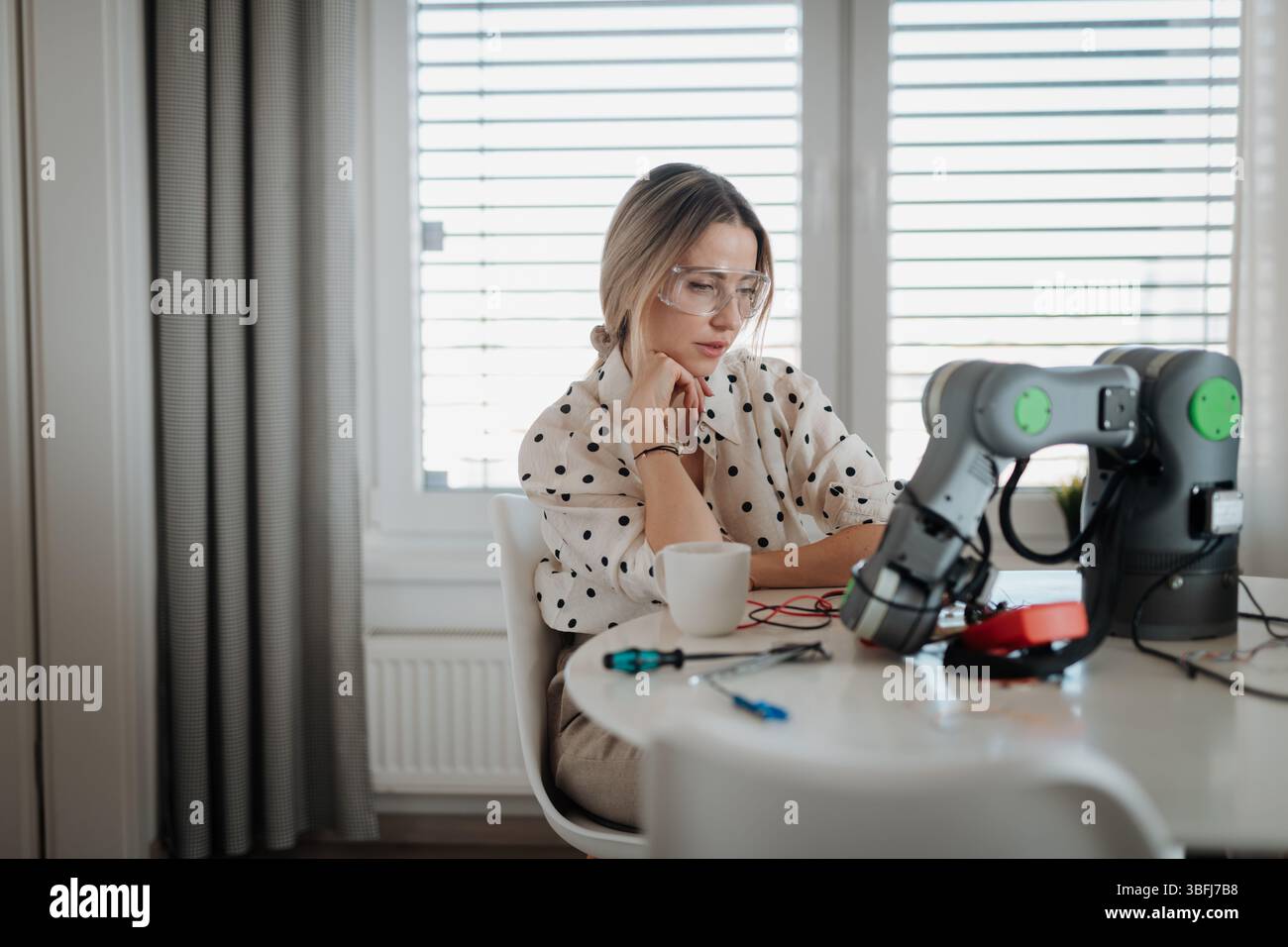 Woman engineer working on robotic arm project at home. Stock Photo