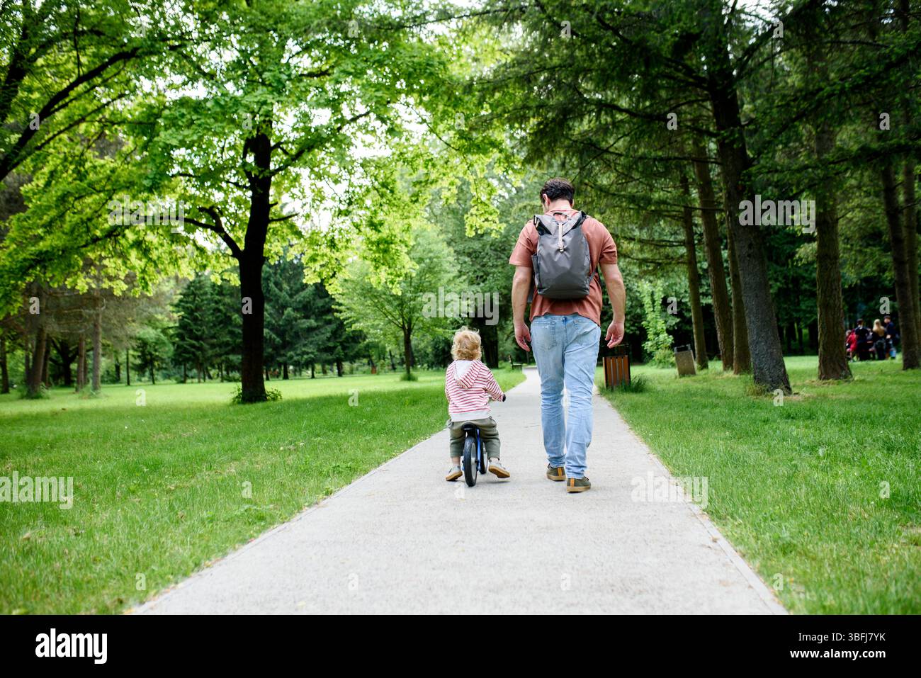 Rear view of father walking with his son across park Stock Photo - Alamy