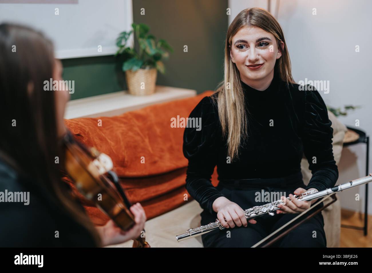 Two young musicians practicing violin and flute together in a cozy room Stock Photo
