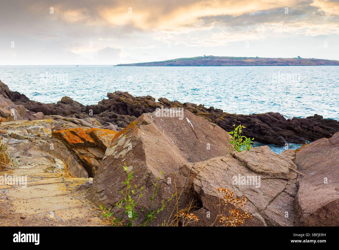 sea rock on the coast. travel nature background with stone on the shore. island on the horizon. beautiful summer vacation at the seaside. calm surface Stock Photo