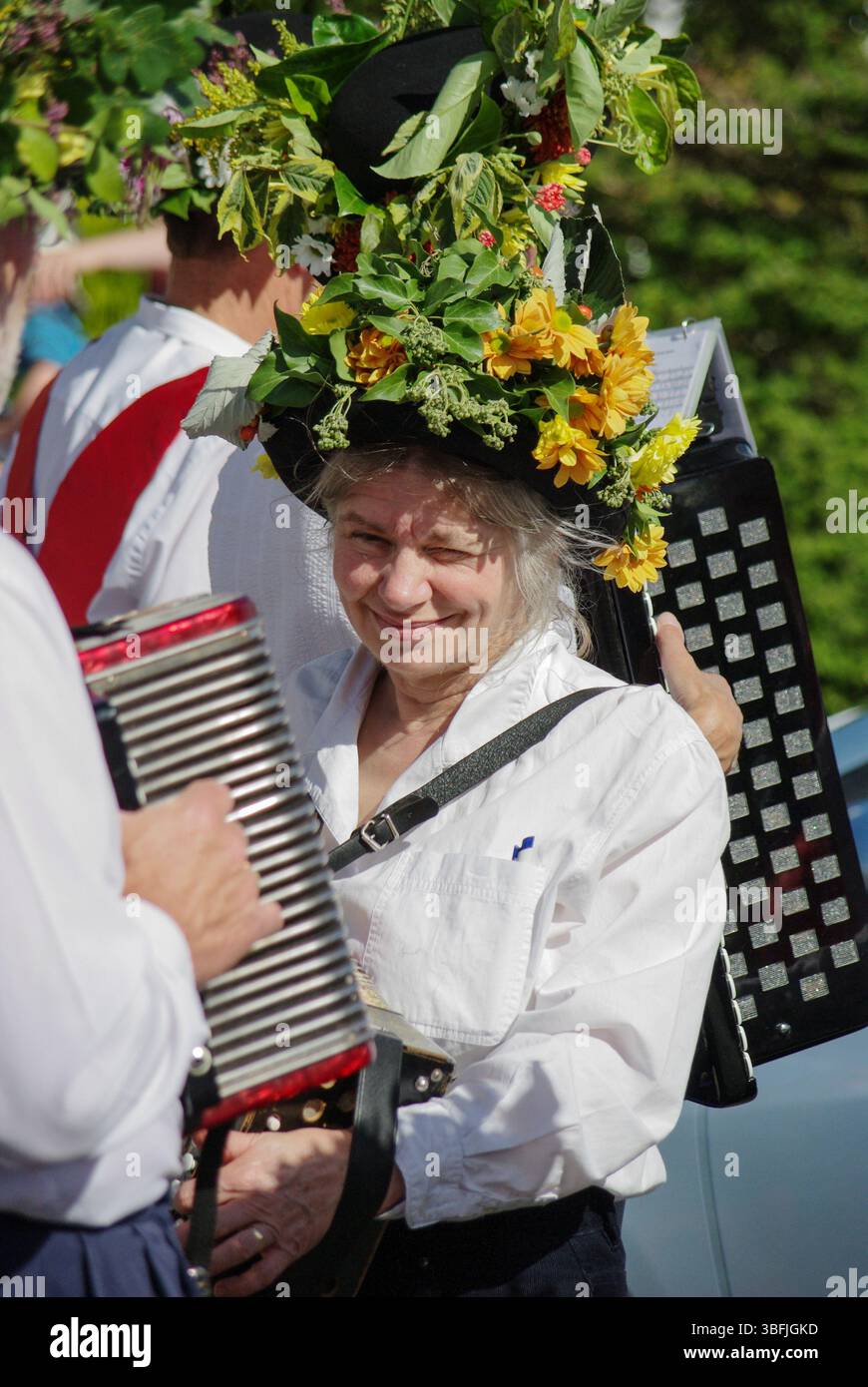 Lady musician in flower decked hat, member of a Morris Dancing group performing in Etal village, Northumberland, UK Stock Photo