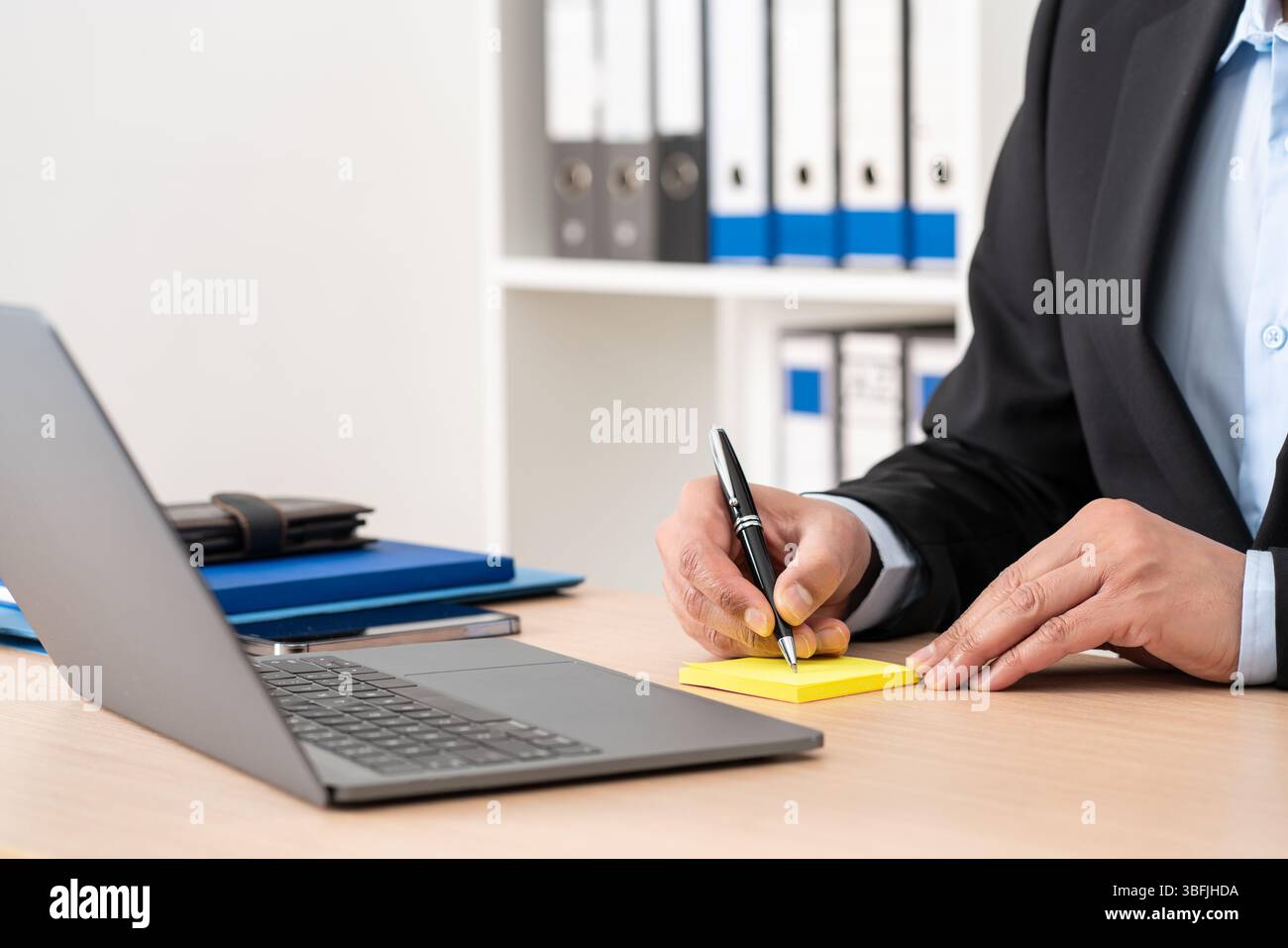 Businessman hand writing on post note at office Stock Photo