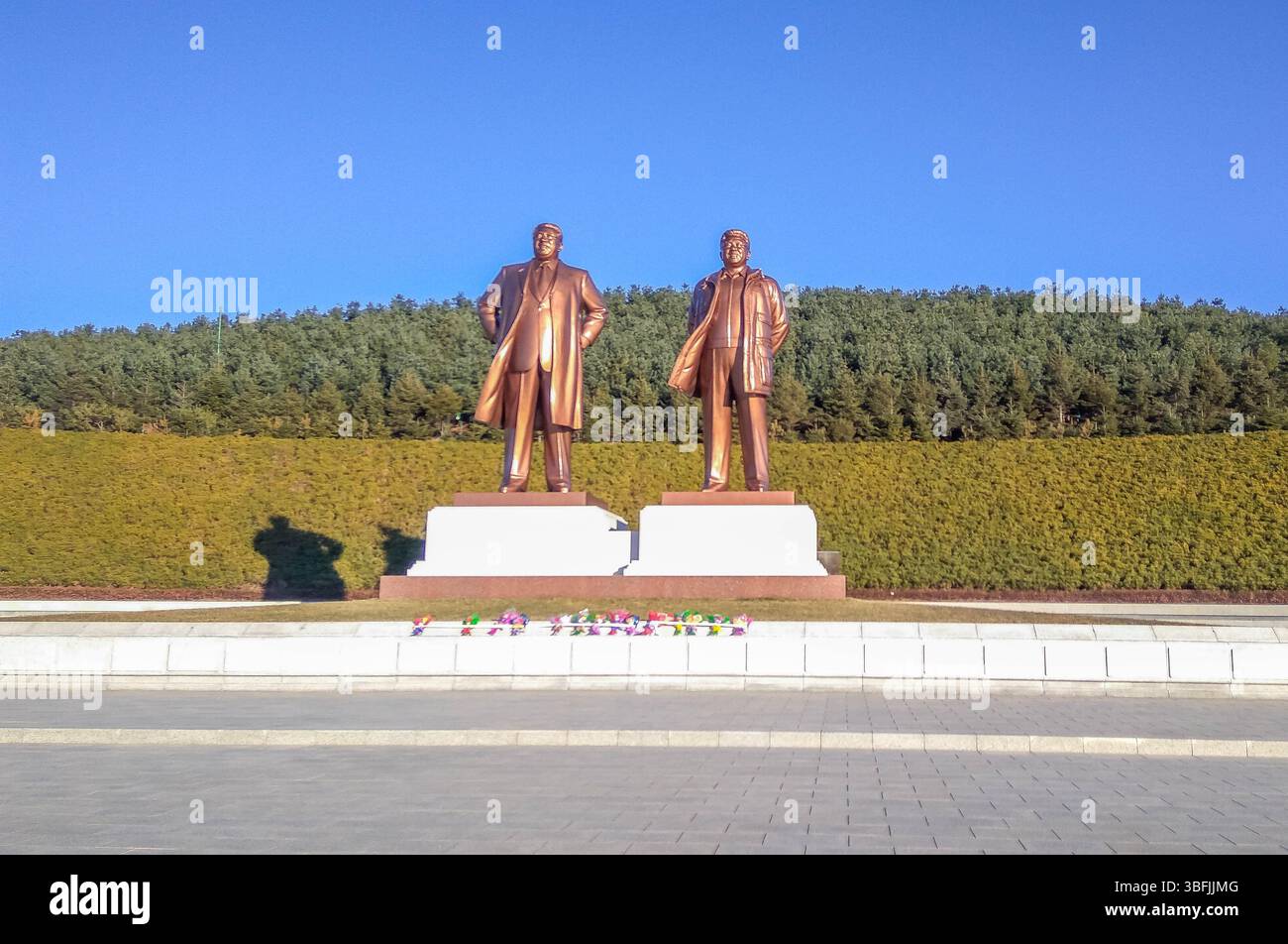 Monumental bronze statues of Kim Il Sung and Kim Jong Il stand in Rajin’s Juche Park, North Korea, a communist ideology landmark. Stock Photo
