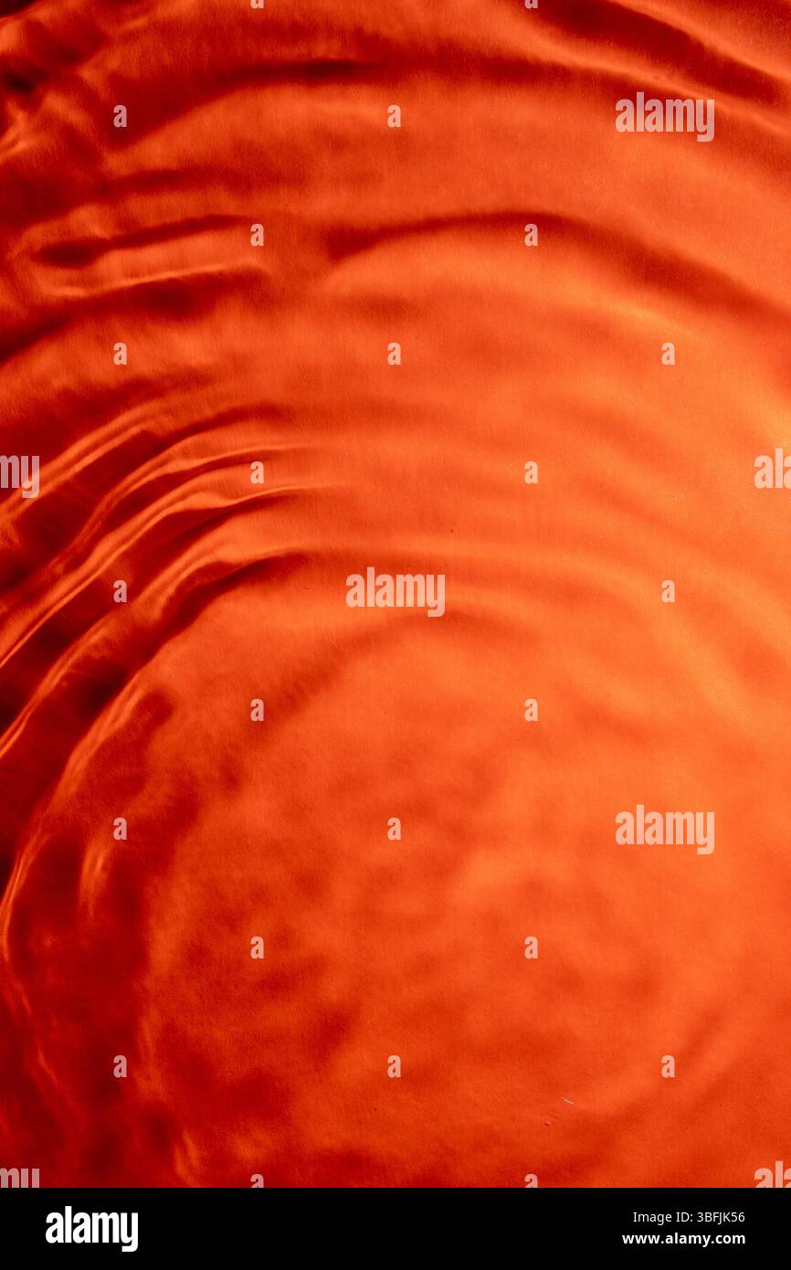 Flowing orange fabric creates a smooth, elegant background Stock Photo