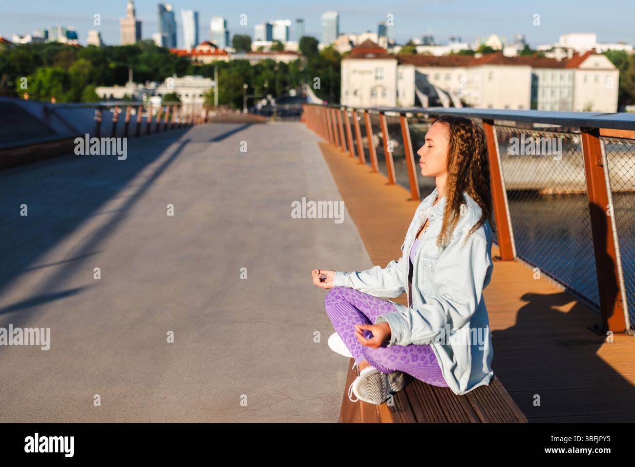 Woman meditating peacefully in urban morning light Stock Photo
