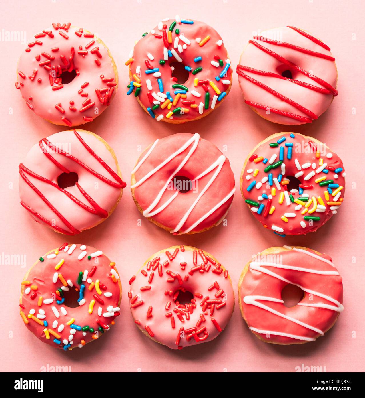 Top view of donuts with pink glaze and sprinkles on pink backdrop Stock ...
