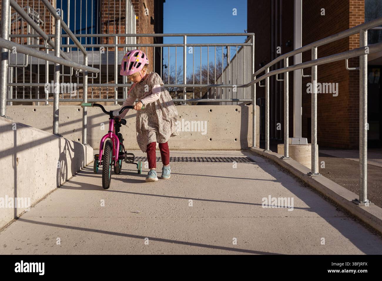 Girl of preschool walking a bike down a ramp Stock Photo - Alamy