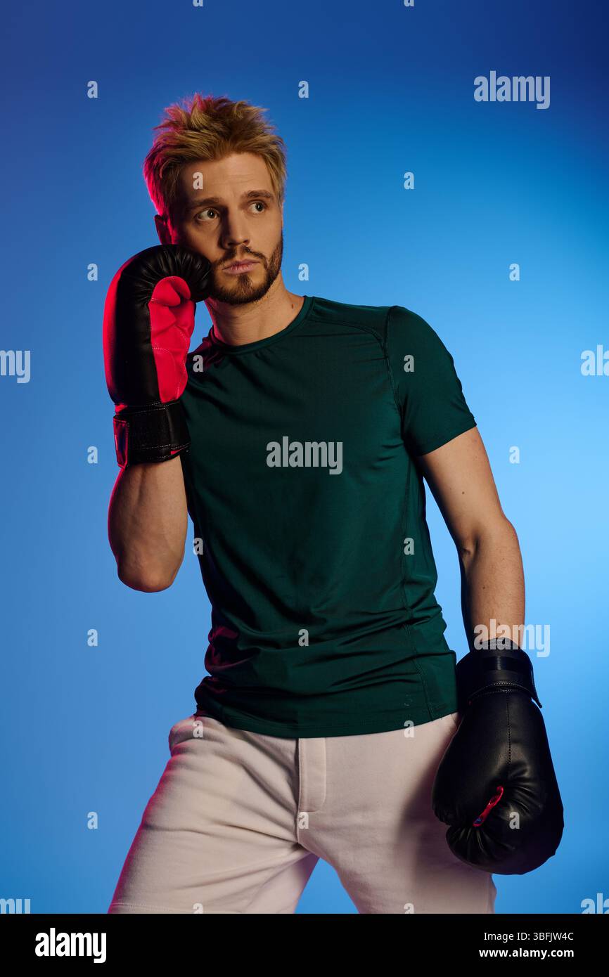 A skilled young man in boxing gloves strikes a confident pose, ready to showcase his talent. Stock Photo