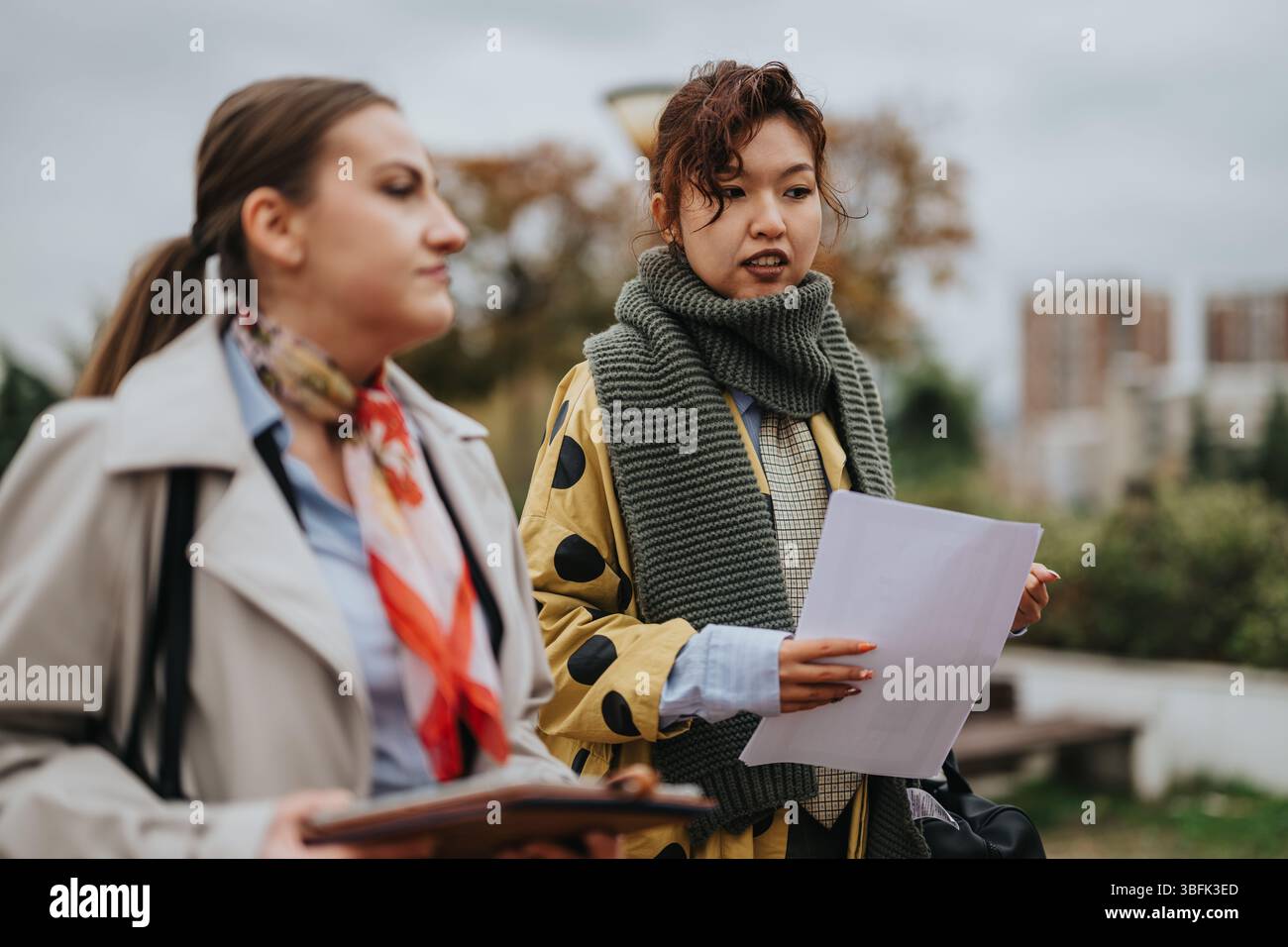 Two people discussing documents during an outdoor meeting in urban surroundings Stock Photo