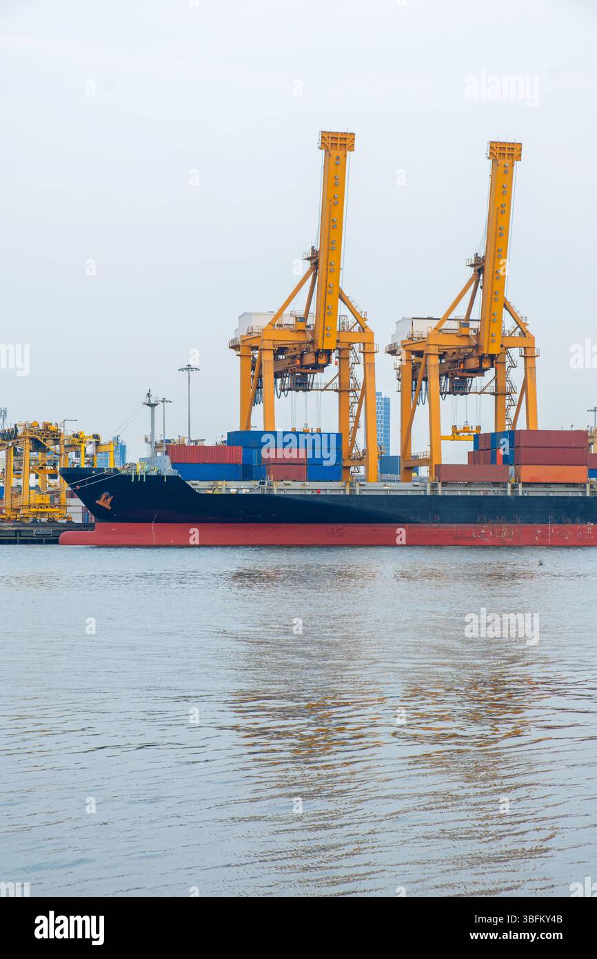 Large container cargo ship docked at port terminal with yellow cranes ...