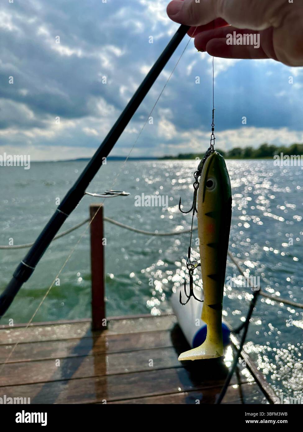 A hand holding a fishing lure at Kummerow lake in Mecklenburg-Vorpommern, Germany - Smartphone Captured Stock Image