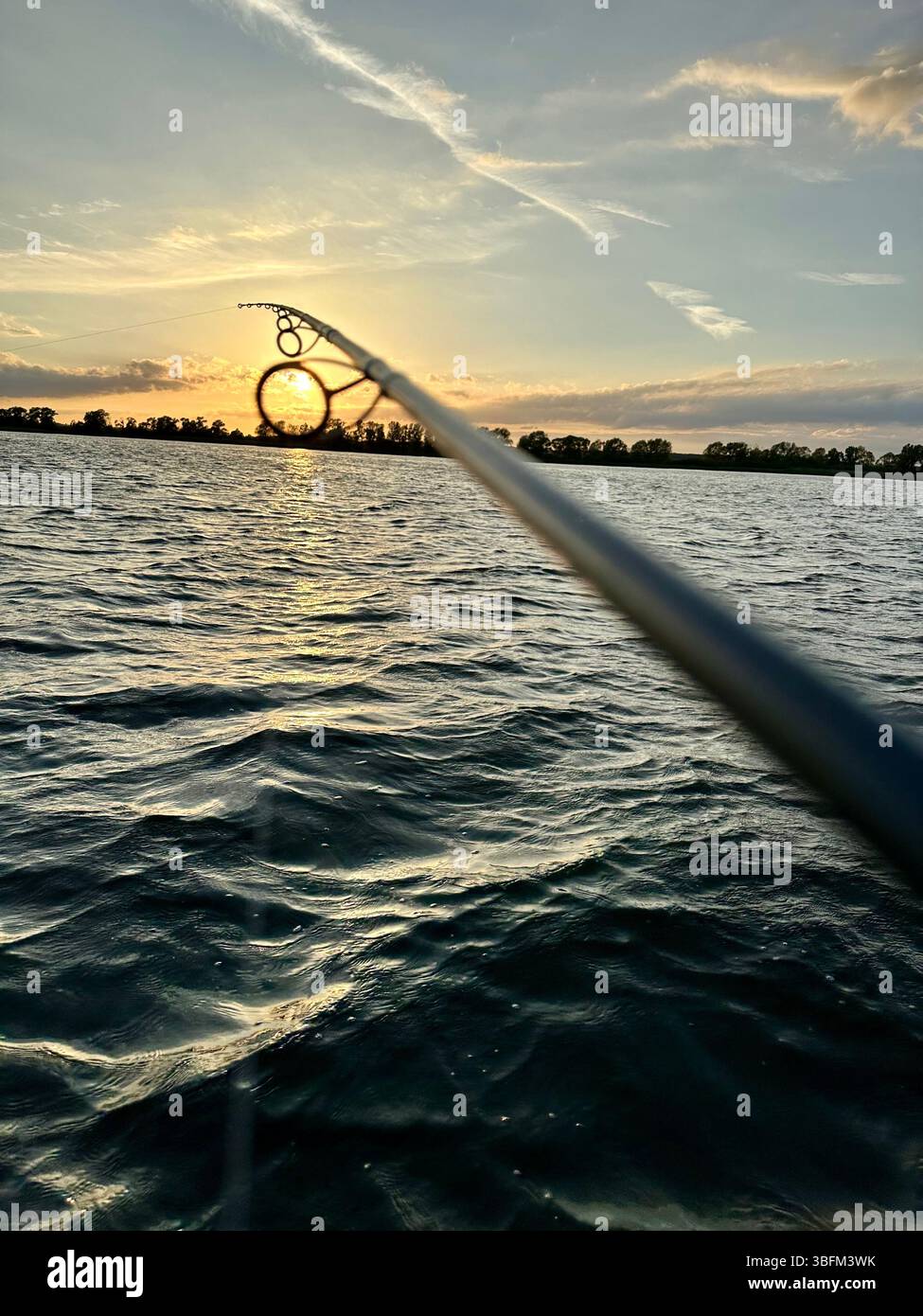 A fishing pole over the water at sunset at Kummerowe See in Mecklenburg-Vorpommer, Germany - Smartphone Captured Stock Image