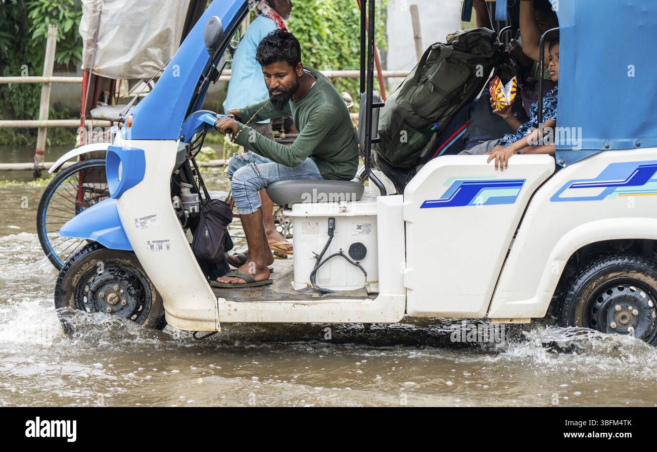 An auto rickshaw driver spit as he passing through a waterlogged street ...