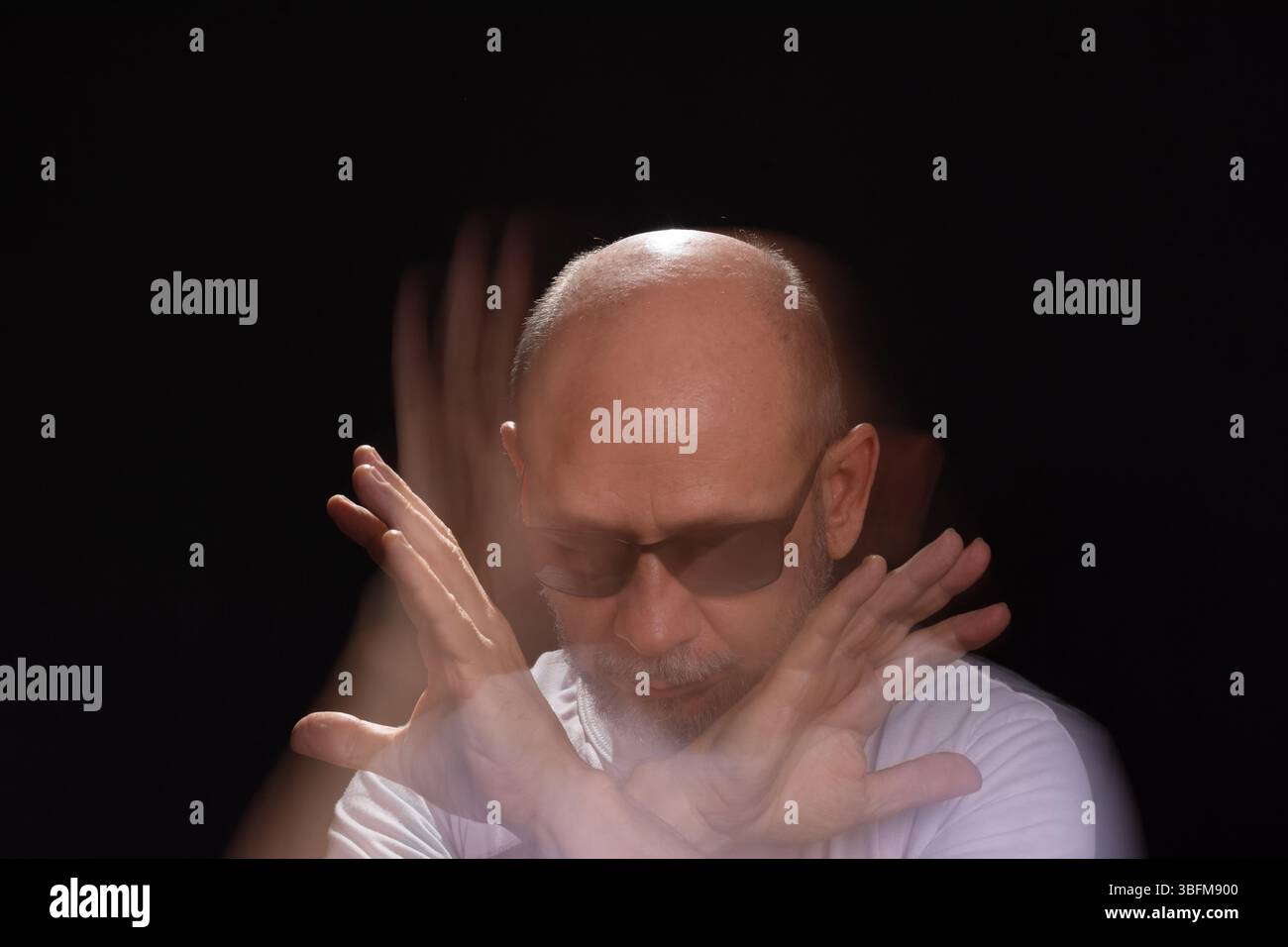 Artistic portrait of bearded bald man in white shirt making motion blur ...