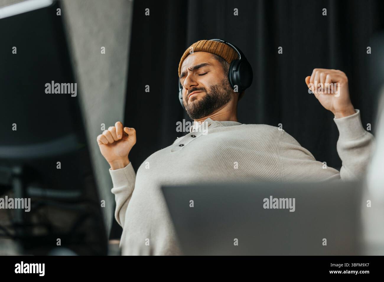 Tired computer programmer stretching while sitting in tech start up office Stock Photo
