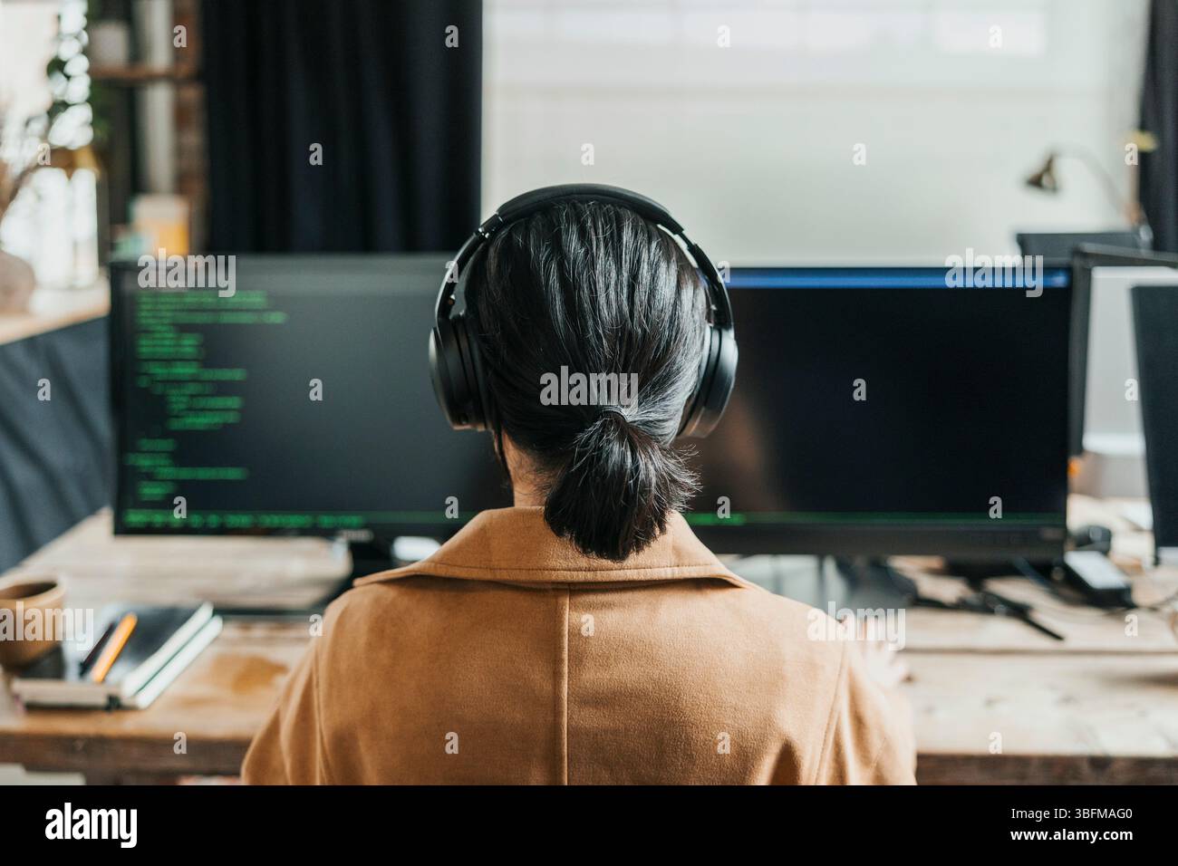 Rear view of computer programmer with ponytail doing coding at tech ...