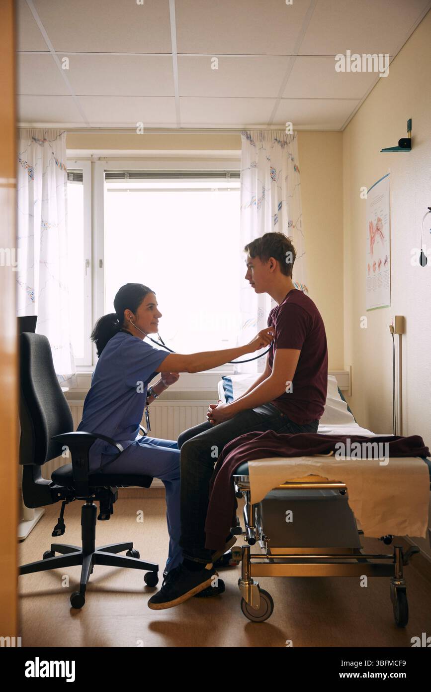 Doctor examining patient with stethoscope in clinic Stock Photo