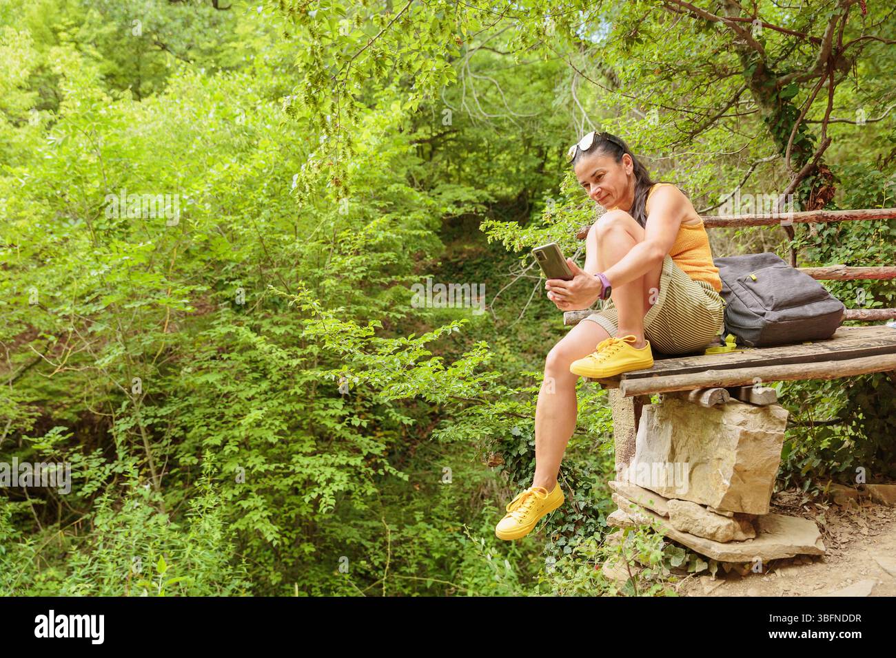 Woman using smartphone for pathfinding in forest Stock Photo