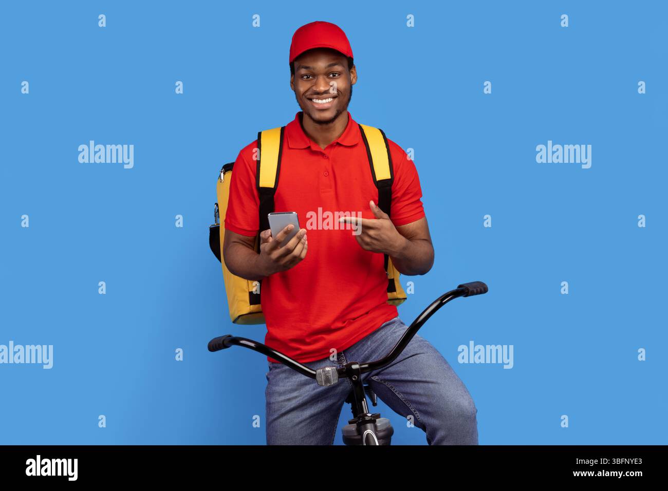 Black delivery man riding bicycle, using smartphone Stock Photo
