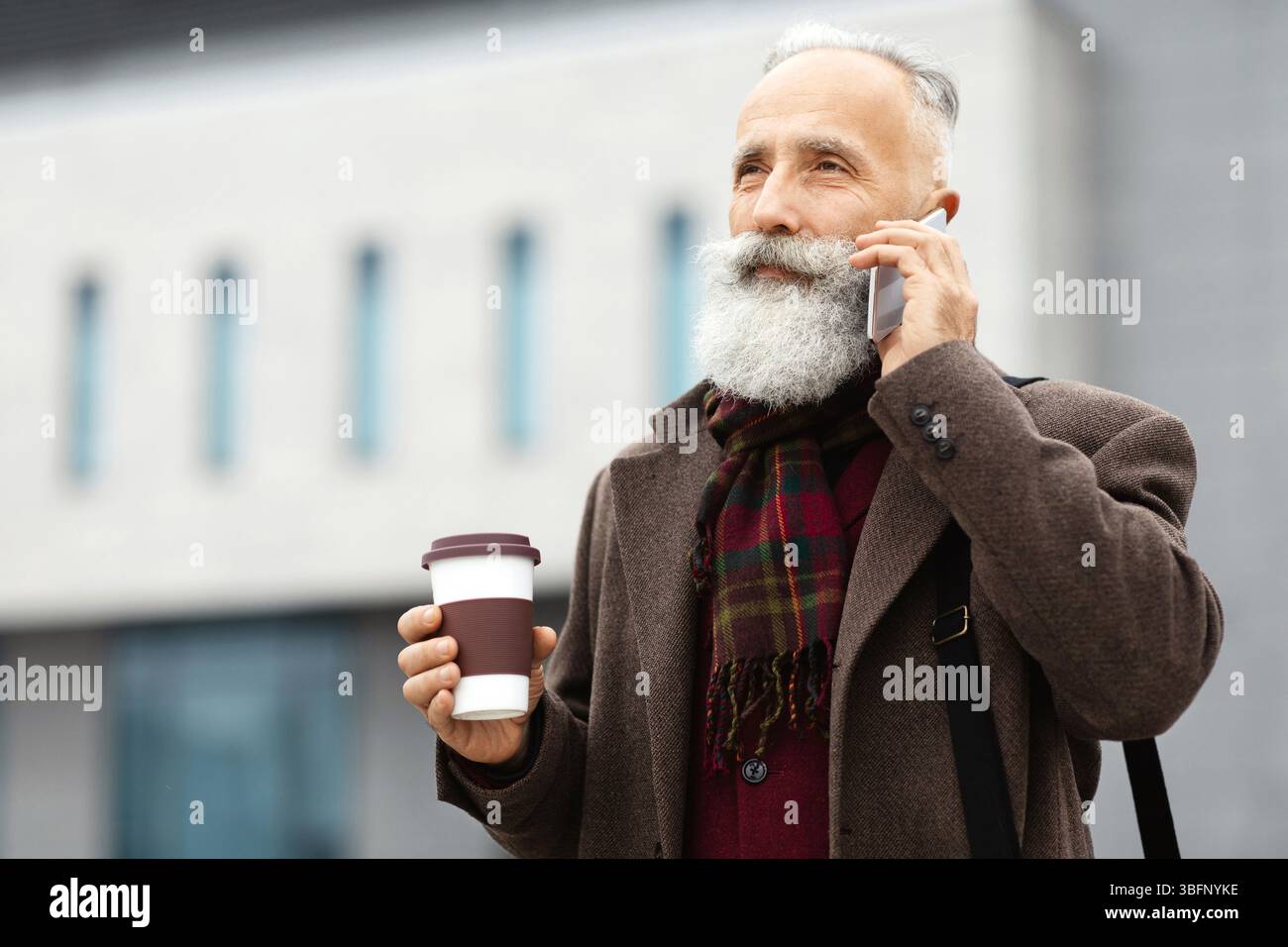 Wealthy senior man with coffee to go having business call Stock Photo