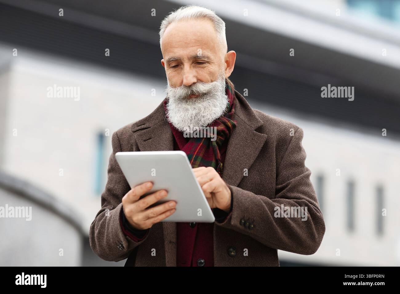 Wealthy senior man using digital tablet outdoors Stock Photo